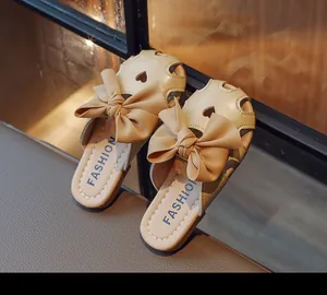 Dettaglio di sabot beige per bambine con un grande fiocco e ritagli a cuore