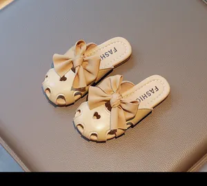 Dettaglio di sandali beige per bambina con fiocco in pelle e decorazione a cuore