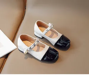 Detail of girls' Mary Jane leather shoes featuring black toe cap and pearl chain accent