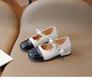 Detail of girls' Mary Jane shoes with black patent leather toe and pearl chain strap