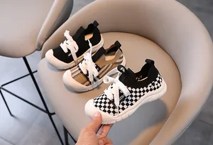 Detail of breathable knitted kids sneakers with checkerboard and solid patterns on a chair