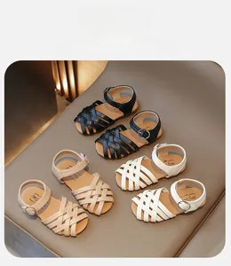 Détail des lanières tressées et boucles sur sandales pour filles en noir, beige et blanc
