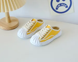 Detail view of yellow canvas mule sneakers with shell toe and chunky wavy rubber sole