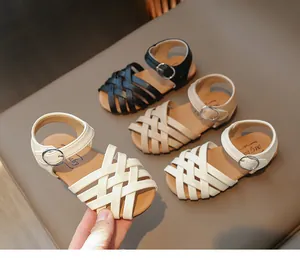 Détail de sandales tressées pour filles en couleurs noir, beige et blanc cassé