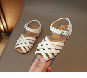 Détail de la tige tressée blanche et boucle argentée sur sandales de plage fille