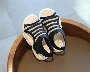 Detail of girls' summer sandals featuring black and white striped mesh and thick white soles