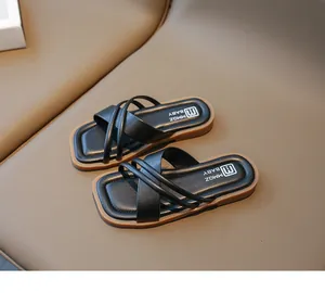 Detailansicht der schwarzen Kindersandalen mit gekreuzten Riemen und weicher brauner Sohle