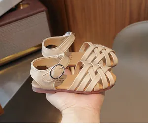 Détail de sandales tressées beige pour tout-petit avec boucle réglable et semelle souple