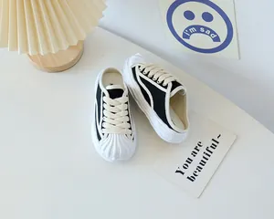 Close-up of black and white canvas mule sneakers for children on a white table