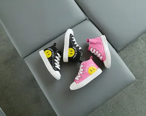 Vista dall'alto di sneakers alte in tela per bambini rosa e nere con logo smiley giallo