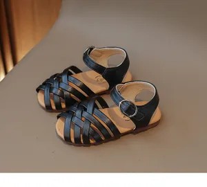 Détail de sandales tressées noires pour filles avec brides croisées et boucle