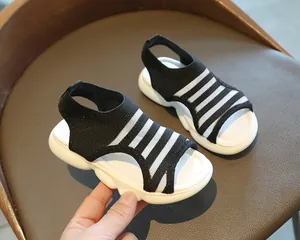 Detailed side view of girls' black and white knit sandals with thick wavy cushioned soles