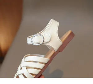 Détail de sandales tressées beige pour filles avec bride cheville et boucle en métal