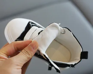 Dettaglio di scarpe alte in tela per bambini con cerniera laterale e punta in gomma bianca