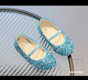 Macro shot of light blue sequined girls flats with elastic strap on glass surface