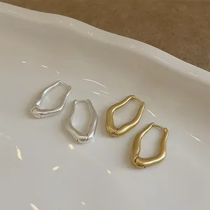 Detailed close-up of irregular wave metal hoop earrings in matte gold and silver finishes