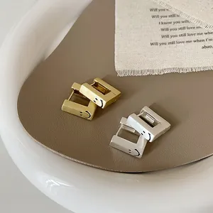 Boucles d'oreilles carrées smiley en or et argent mat sur un plateau en céramique