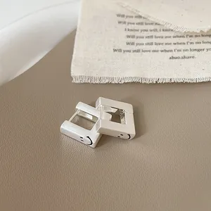 Vue détaillée des boucles d'oreilles carrées en argent brossé avec symbole de sourire gravé