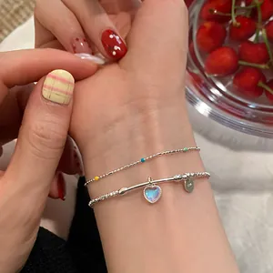 Detalle de pulsera de doble capa en plata S925 con colgante de corazón colorido
