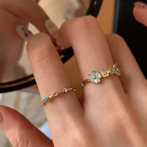 Detailed close-up of gold flower rings featuring blue zircon accents and floral design