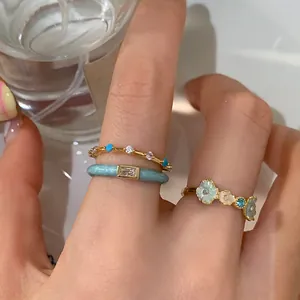 Macro shot of blue enamel flower ring and gold band rings with colorful zircons