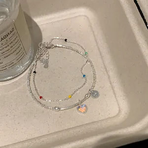 Detalle de pulsera de plata de doble capa con corazón, cuentas de colores y sello S925