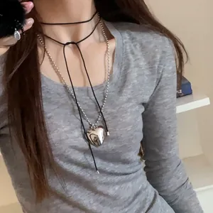 Détail du collier cœur superposé et du ras-de-cou à nœud en velours sur haut gris