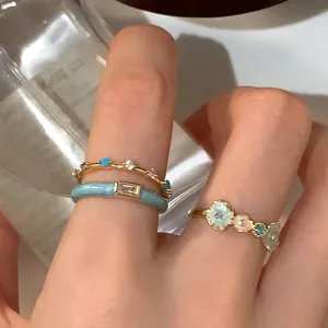 Detailed close-up of blue enamel flower ring set with zircons on finger