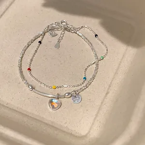 Detalle de pulsera doble de plata S925 con cuentas de colores y un colgante de corazón