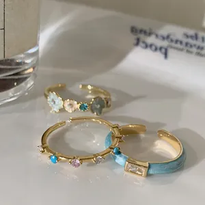 Detailed macro view of three adjustable blue enamel flower rings with zircon stones