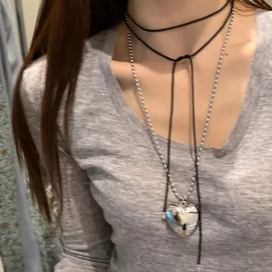 Détail du collier ras de cou noir avec chaîne à boules argentée et pendentif cœur
