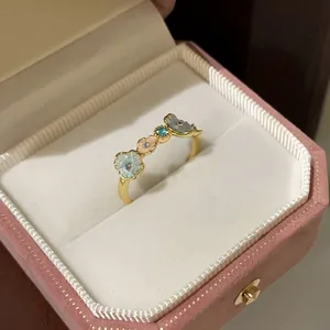 Macro shot of gold floral ring with blue enamel petals in a pink velvet jewelry box