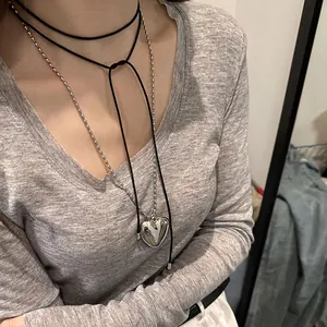 Détail d'un choker en velours noir à nœud avec un pendentif cœur en argent poli