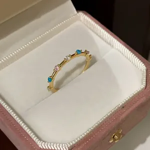 Close-up of gold flower ring with blue and pink stones in a pink velvet jewelry box