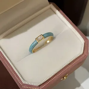 Macro detail of gold flower ring with blue enamel texture and rectangular zircon stone