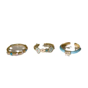 Three-piece gold ring set featuring blue enamel flower and colorful zircon stones
