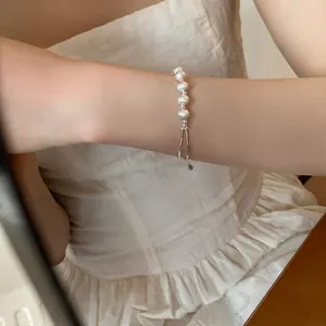 Detail of elegant white pearl bracelet on wrist with silver clasp and small pendant charm