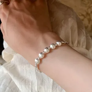 Close-up of brushed silver beaded bracelet with polished spacers on a model wrist