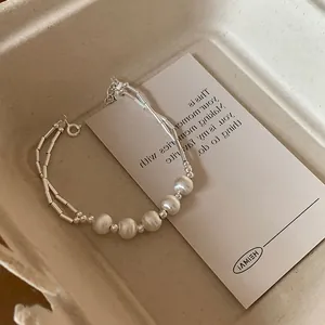 Detailed shot of silver double-strand bracelet with pearls and cylindrical metal beads