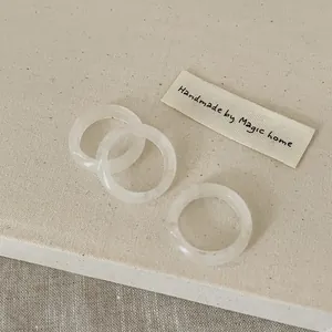 Detailed top view of three minimalist translucent resin rings on a textured linen background