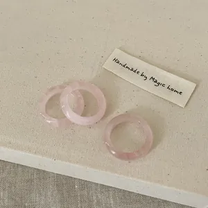 Detailed view of three faceted pink crystal resin rings on a textured beige fabric background