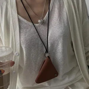Detail of vintage triangular leather pouch pendant and heart charm on silver bead chain