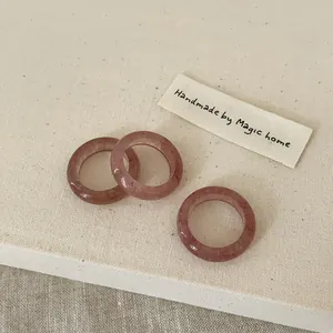 Close-up of three handmade pink natural crystal rings with polished resin texture
