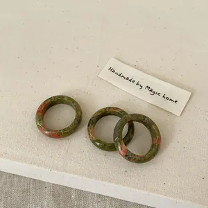 Detailed macro view of three unakite natural stone rings on rustic linen background