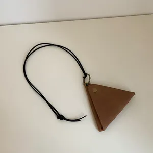 Macro detail of retro brown triangular leather pouch with brass snap and black lanyard