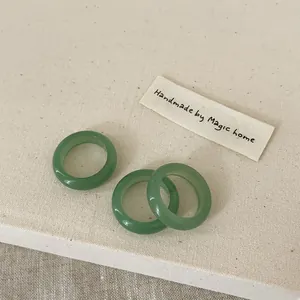 Detailed close-up of three minimalist light green crystal stone rings on a fabric texture