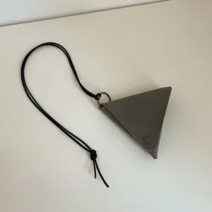 Macro shot of grey triangle leather neck pouch with bronze snap button and black cord