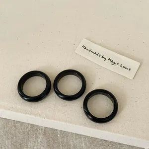 Three handmade black resin rings on textured linen fabric, minimalist smooth finish