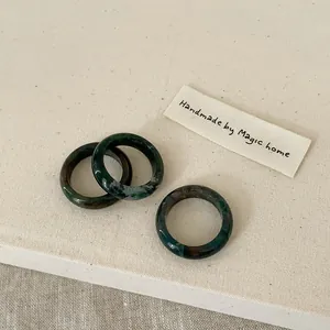 Detailed view of three polished dark green natural stone rings with unique marbled textures