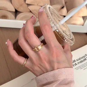 Détail d'une bague double boucle en métal brossé doré avec oxydes de zirconium incrustés